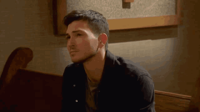 a man in a black jacket is sitting on a bench