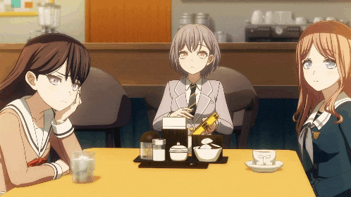 three girls are sitting at a table with a yellow table cloth