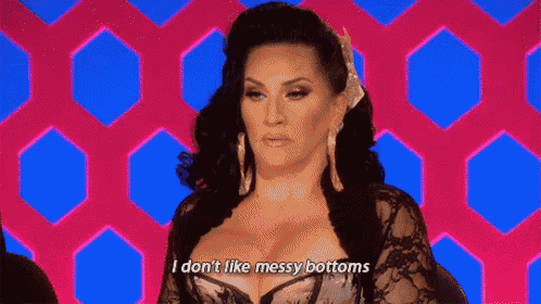 a woman with large breasts is standing in front of a pink and blue background .