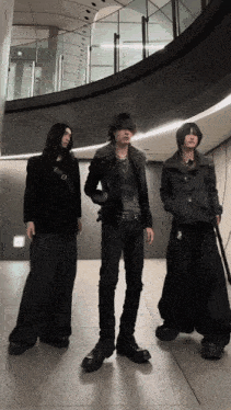 three men are standing next to each other in front of a glass wall