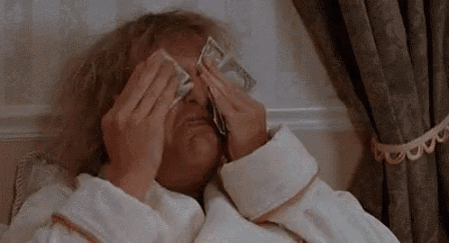a man in a bathrobe is covering his eyes with a bunch of money .