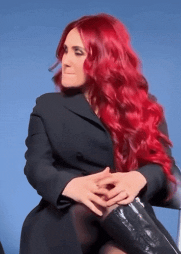a woman with red hair wearing a black jacket and black boots