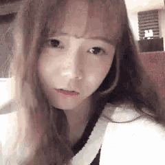 a close up of a girl with long hair making a funny face while looking at the camera .