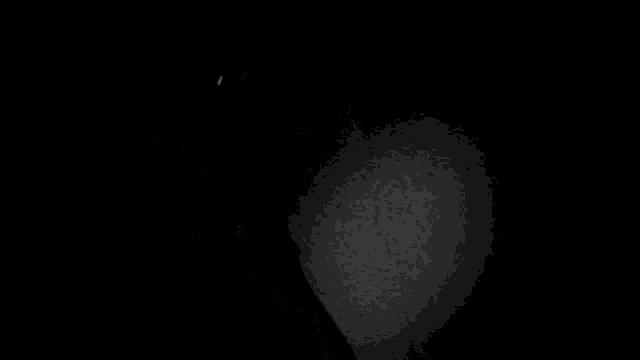 a black and white photo of a man with a surprised look on his face in a dark room .