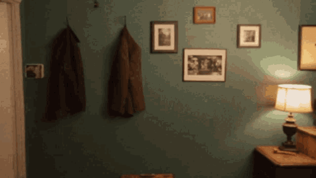 a room with pictures on the wall and a lamp on a nightstand