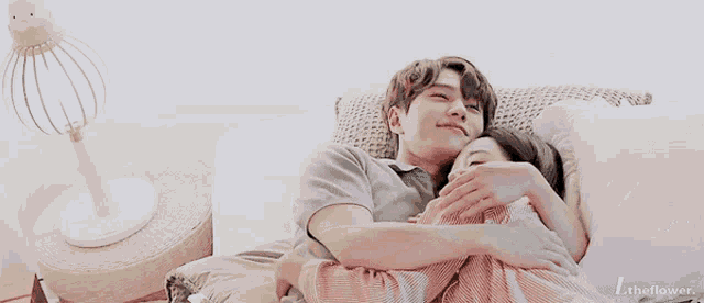 a man and woman are hugging each other while laying on a bed .