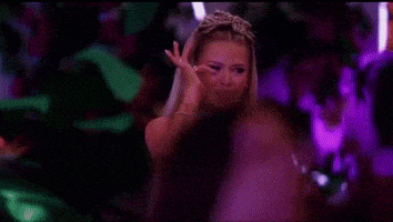 a woman wearing a tiara and a white top is making a peace sign