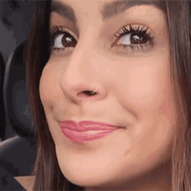 a close up of a woman 's face with a nose ring and pink lips