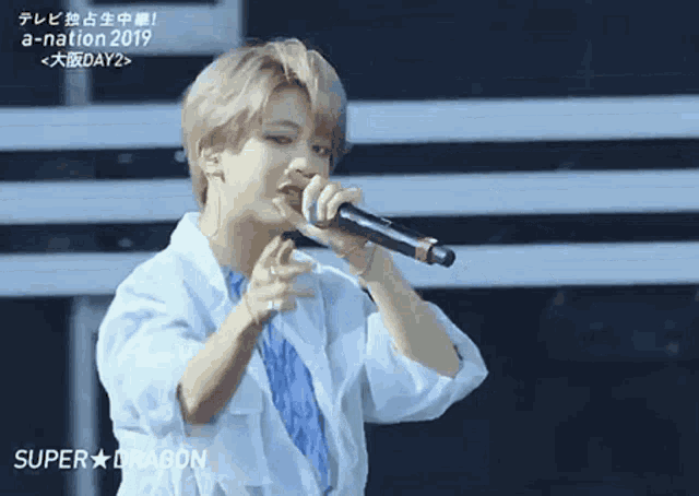 a young man singing into a microphone with super dragon written in the corner