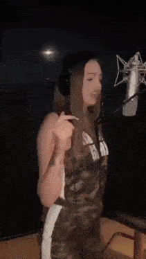 a woman singing into a microphone wearing a camo outfit