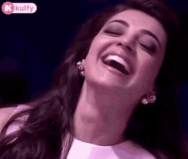 a woman is laughing with her mouth open and her eyes closed .