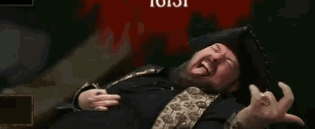 a man with a beard wearing a pirate hat is laying on the ground and laughing .