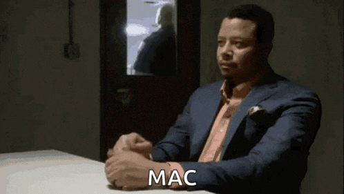 a man in a scrub suit is sitting at a desk in a dark room .