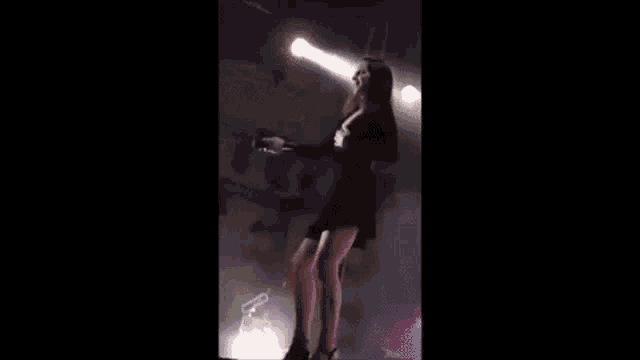 a woman in a black dress is standing on a stage holding a microphone in her hand .