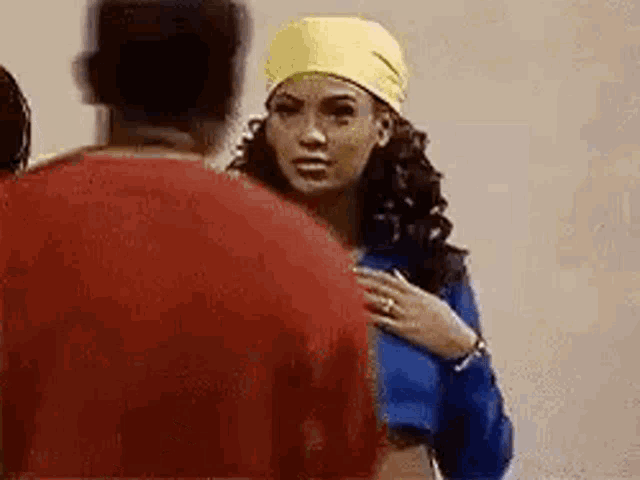 a man and a woman are standing next to each other and the woman is wearing a yellow head scarf .