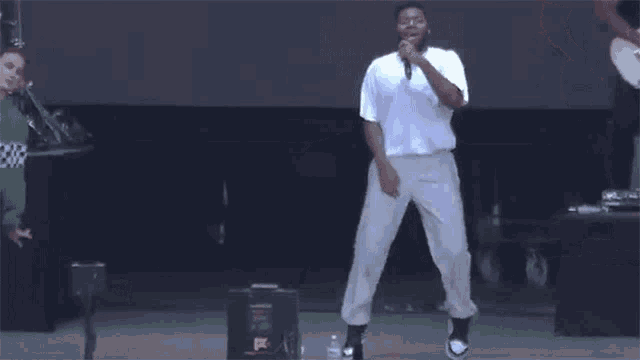 a man is singing into a microphone on a stage while dancing .