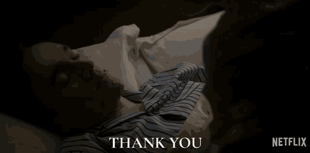 a man in a striped shirt is laying in bed and says thank you