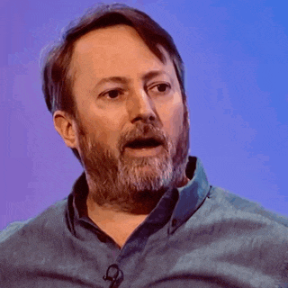 a man with a beard is wearing a blue shirt and a microphone