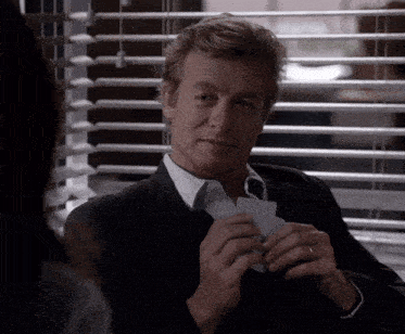 a man in a suit is holding a playing card in his hand