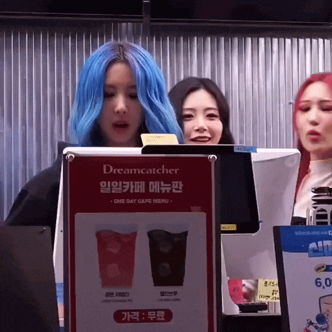 a woman with blue hair is standing in front of a dreamcatcher sign
