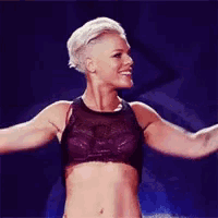 a woman in a crop top is dancing on a stage .