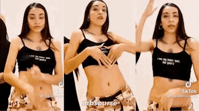 a woman in a black crop top and camo shorts is making a heart shape with her hands .