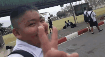 a boy is making a peace sign in front of a group of children