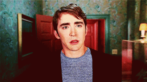 a man making a surprised face in front of a red door