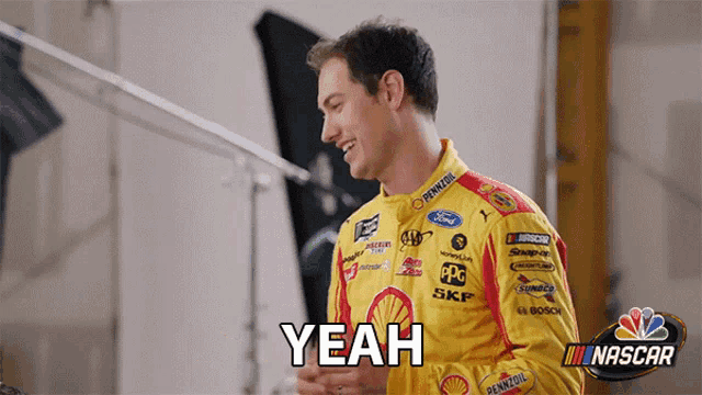 a man in a nascar uniform says yeah while smiling