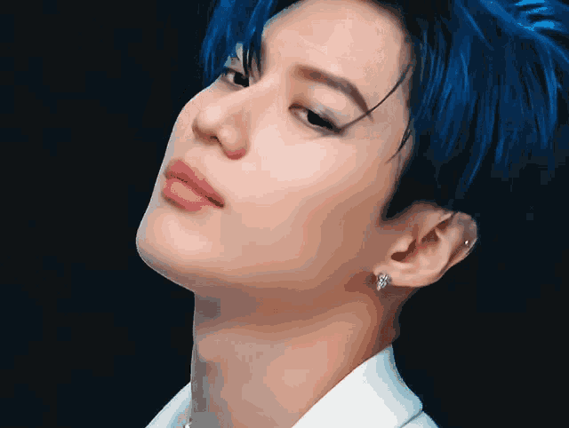 a man with blue hair is wearing a white shirt and earrings