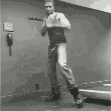 a man is standing on a treadmill holding a bat in his hands .