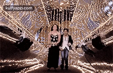 a man and a woman are standing next to each other in a room filled with lights .