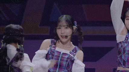 a group of girls are dancing on a stage and one of them is wearing a plaid dress .