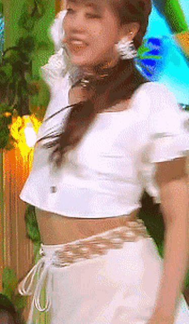a woman in a white top and white shorts is dancing .