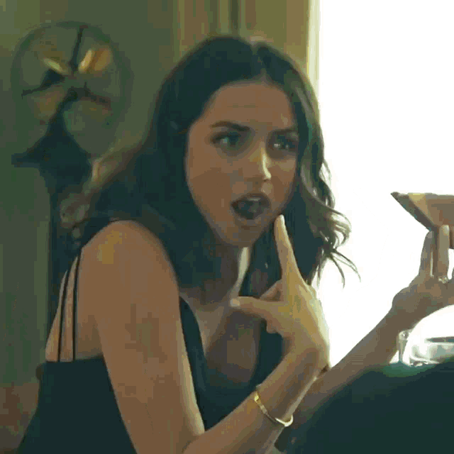 a woman in a black dress holds a martini in her hand