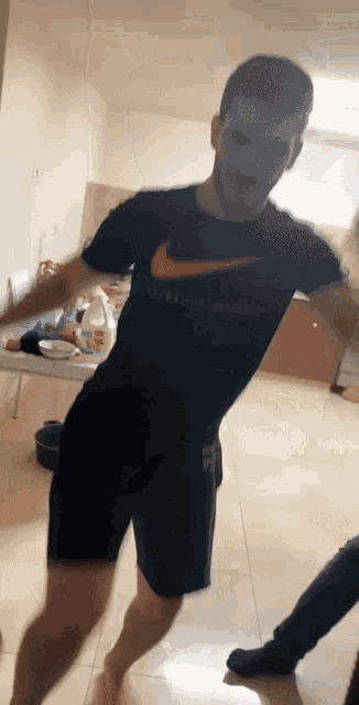 a man in a black nike shirt is dancing in a kitchen