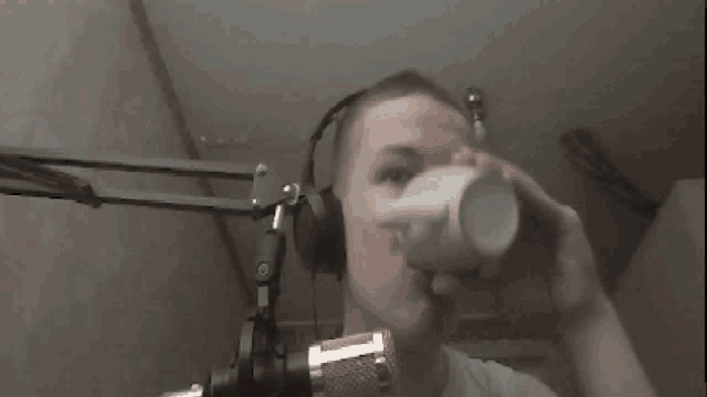 a man wearing headphones is drinking from a cup