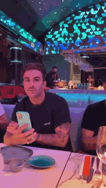 a man sitting at a table with a cell phone in his hand .