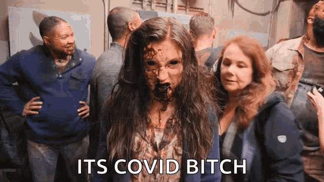 a woman with blood on her face is standing in a crowd and says its covid bitch .