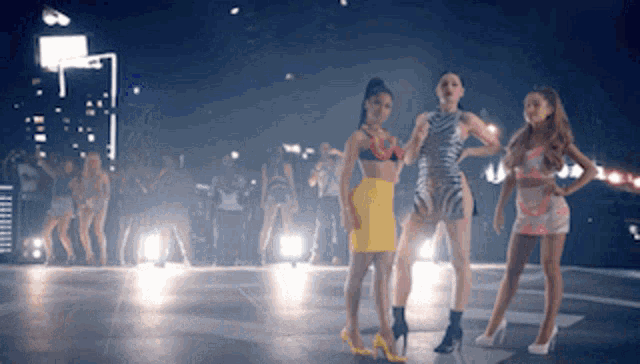 a group of women are standing on a dance floor in front of a crowd