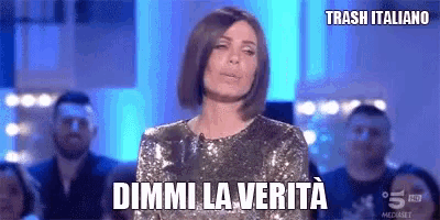 a woman in a sequined dress is standing in front of a crowd and says dimmi la verita .