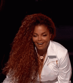a woman with red curly hair is wearing a white shirt and necklace .