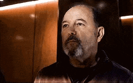 a man with a beard is looking up in an elevator .