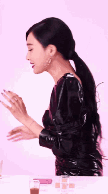 a woman in a black leather dress is standing in front of a pink wall