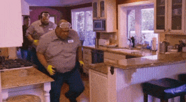 a man wearing a name tag is standing in a kitchen with two other men