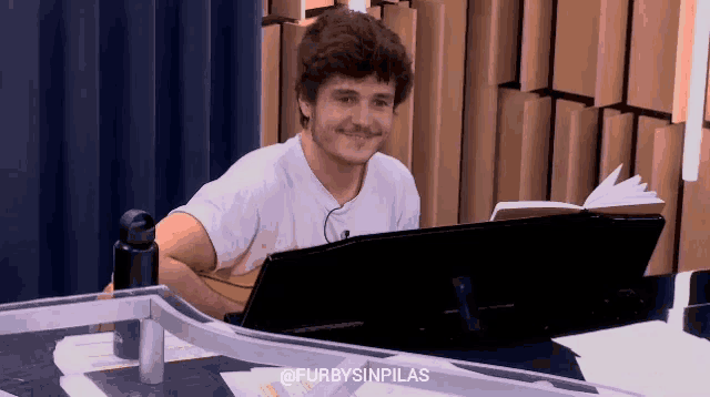 a man is sitting at a desk with a laptop and a book and the hashtag furbysinpilas
