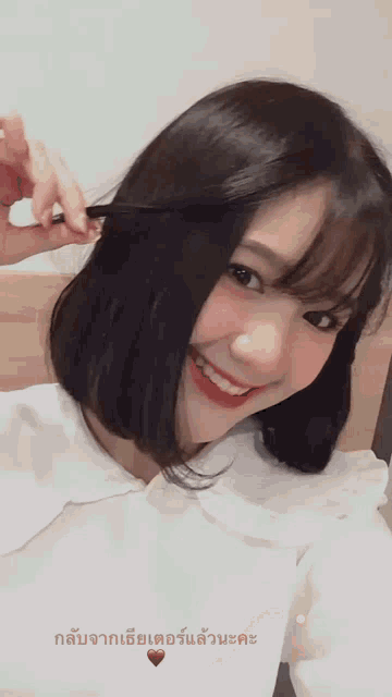 a woman with short hair is smiling and holding her hair in her hand