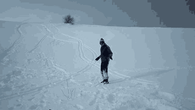 a man is kneeling in the snow with his arms outstretched and pointing