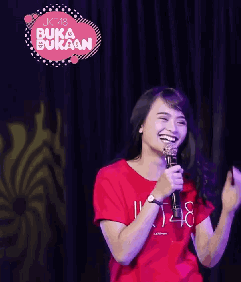 a woman singing into a microphone with a sign that says buka bukan