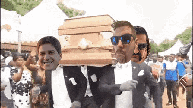 a man in a tuxedo is carrying a coffin with three men 's faces on it